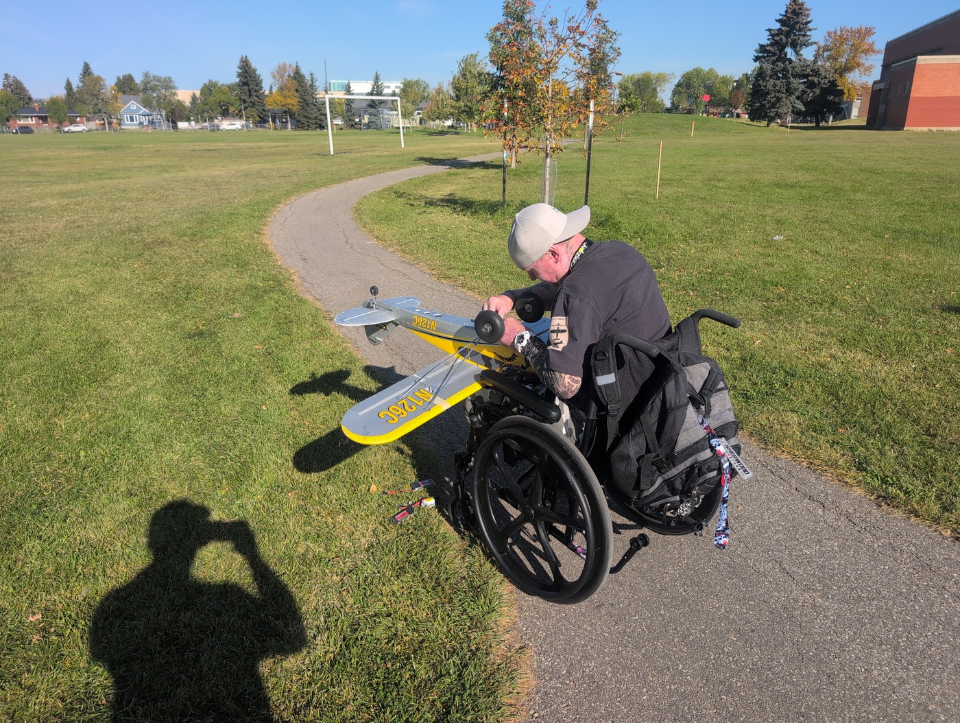 Chris holding the transmitter behind the yellow and silver plane on the path